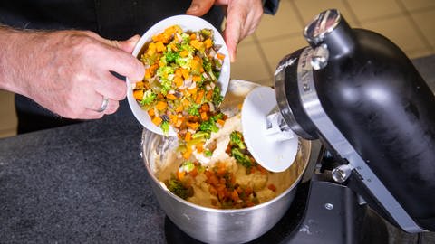 Das zubereitete Gemüse kommt zu dem Teig für den Gugelhupf in die Rührschüssel und macht so den Kuchen herzhaft.