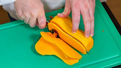 Der Butternut-Kürbis wird für das Rezept mit den Linsen in feine Scheiben geschnitten, nachdem er entkernt und geschält wurde.