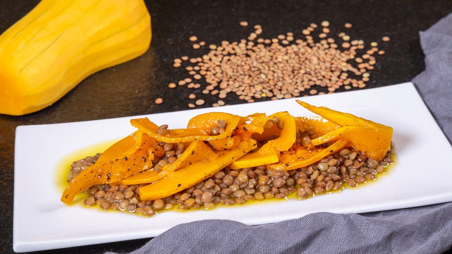 Karamellisierter Kürbis ist auf einem Salat mit Linsen angerichtet. Im Rezept gibt der Butternut den Alblinsen Farbe und süßlich-fruchtigen Geaschmack.