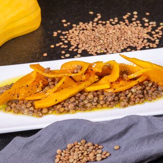 Karamellisierter Kürbis ist auf einem Salat mit Linsen angerichtet. Im Rezept gibt der Butternut den Alblinsen Farbe und süßlich-fruchtigen Geaschmack.