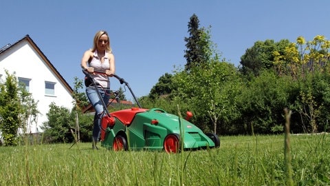 Eine Frau mäht in ihrem Garten.