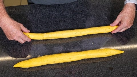 Der Teig aus Kürbis wird in zwei Teile portioniert. Anschließend wird er zu einem Baguette geformt. Die Farbe hat das Brot vom Hokkaido.