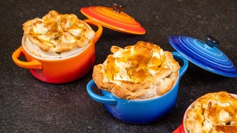 Drei Pies mit einer Füllung aus Pilzen in zwei roten und einer blauen Form für Pasteten an deren je ein Deckel angelehnt ist. Der Pie lässt sich vielfältig befüllen.