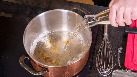 Karamellisierter Puderzucker wird in einem Topf mit Wein und Wermut abgelöscht.