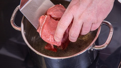 Die Fleisch-Stücke von der Kalbsschulter werden in Wasser gelegt und zum Kochen gebracht.