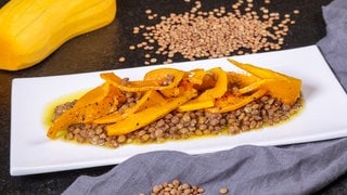 Karamellisierter Kürbis ist auf einem Salat mit Linsen angerichtet. Im Rezept gibt der Butternut den Alblinsen Farbe und süßlich-fruchtigen Geaschmack.