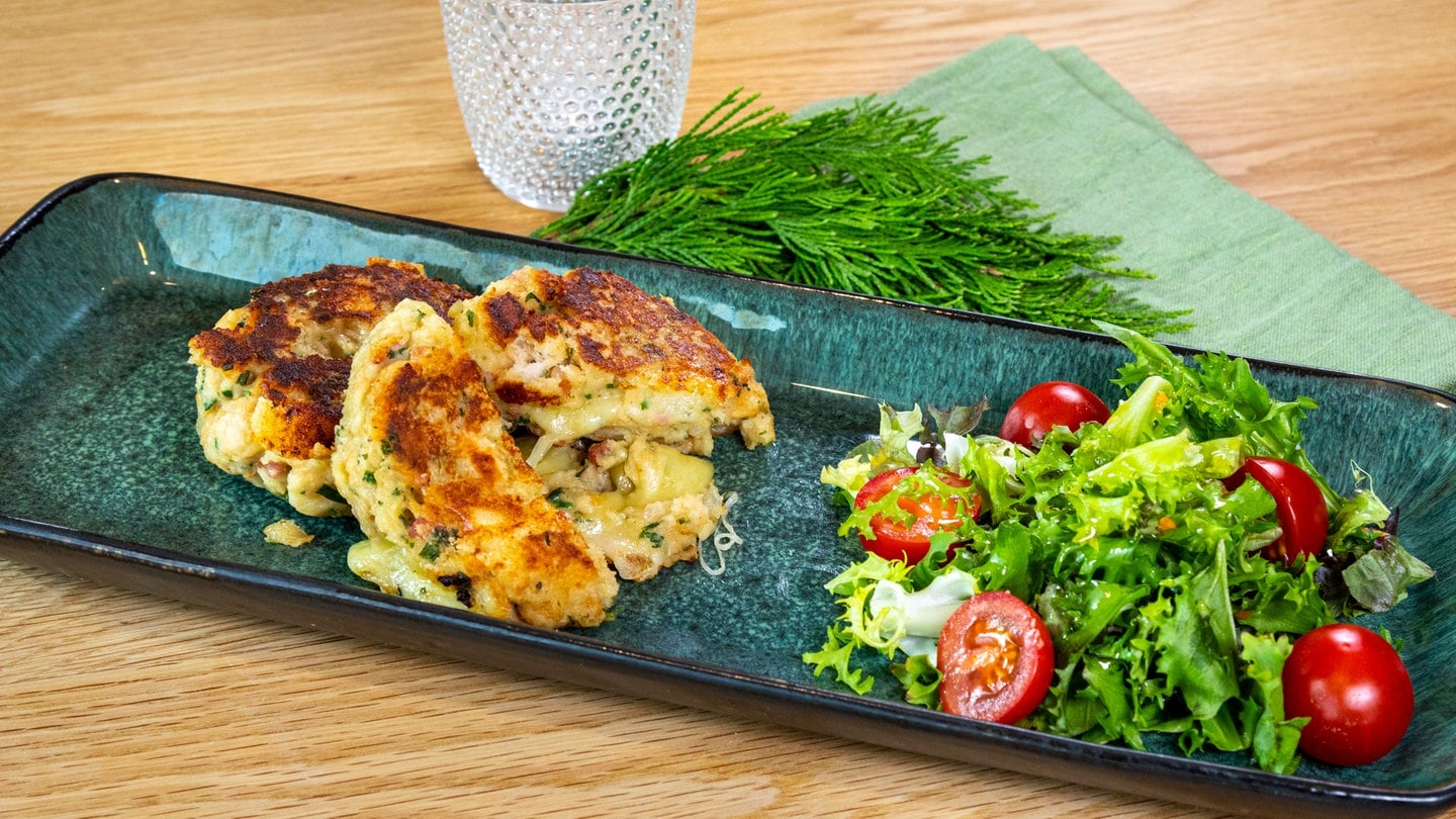 Leckere Kaspressknödel auf einem Teller mit Salat. Die Käseknödel sind schön angebraten.