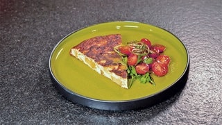 Spanische Tortilla nach einem einfachen Rezept mit Kartoffeln und Lauch auf einem Teller mit Tomatensalat.