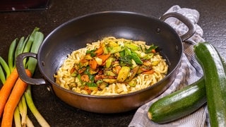 Rahmspätzle mit Pesto und Gemüse in einer Pfanne.