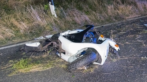 Ein Motoroller liegt zerschmettert auf der Straße bei Dunkelheit.