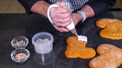 Nikolausstiefel backen: Auf den oberen Rand der Stiefel wird der Zuckerguss mit einer Spritztüte aufgetragen.