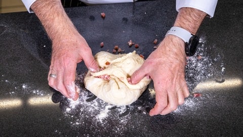 Herzhaftes Baguette mit Speckwürfel backen: Den Teig in eine Kugel formen und die Speckwürfel unterheben.