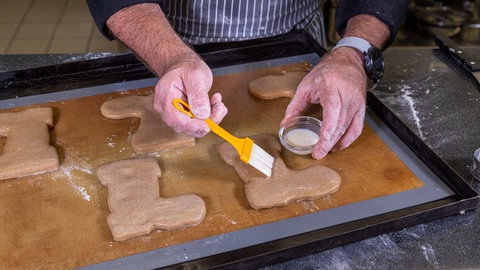 Nikolausstiefel backen: Die ausgestochenen Stiefel werden mit Glasur bestrichen.