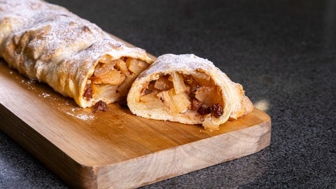 Rezept für leckeren Apfelstrudel: Ein leckerer Apfelstrudel angeschnitten und mit Puderzucker dekoriert