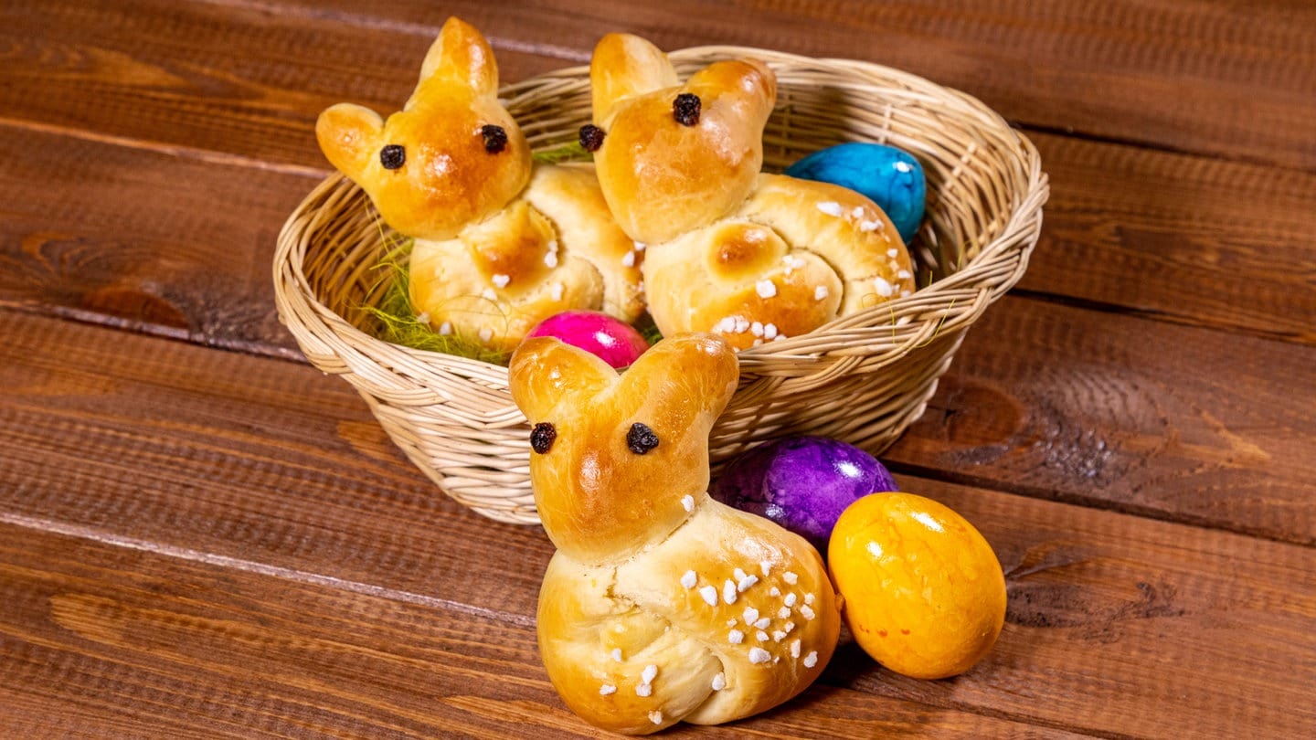 Rezept für Ostergebäck: Zu Ostern Osterhasen aus Hefeteig in einem Osternest mit bunten Eiern.