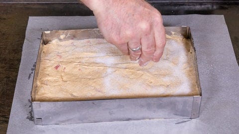 Wie im Rezept beschrieben wird die Rhabarberschnitte vor dem Backen ganz einfach und schnell mit Zucker bestreut.