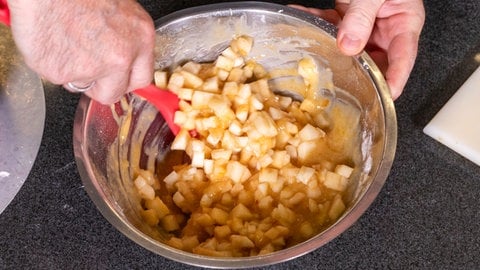 Birnenwürfel werden mit einem Kochlöfel unter die Quittenmasse gehoben