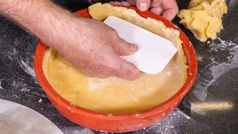 Der Teig wird für den Quitten-Birnenkuchen in eine Tarte-Form ausgelegt. 