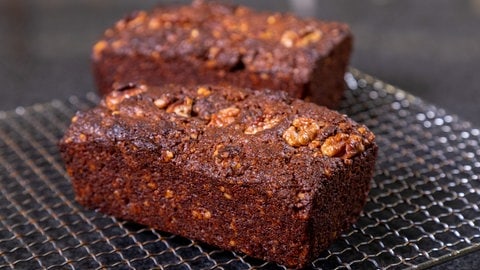 Der vegane Kuchen mit Walnuss ist fertig gebacken und kühlt auf einem Backgitter aus. Im Inneren ist er saftig.