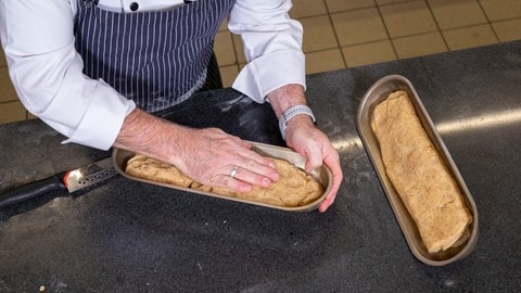 Der Teig für den Marzipanstollen wird in Stollenformen gegeben. 