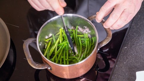 Rezept für Forellenfilet geräuchert als Vorspeise: Bohnen und Schalotten werden in einem Topf angeschwitzt.