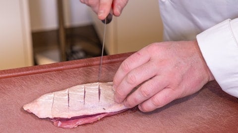 Entenbrust in Orangensauce mit Wirsing: Die Entenbrust wird mit einem scharfen Messer an der Haut eingeschnitten.