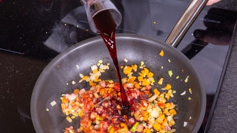 Entenbrust in Orangensauce mit Wirsing: Das Gemüse für die Sauce wird mit Rotwein abgelöscht.