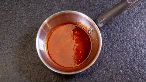 Entenbrust in Orangensauce mit Wirsing: Ein Topf mit der fertigen Sauce für das Weihnachtsmenü steht auf einer Arbeitsplatte.