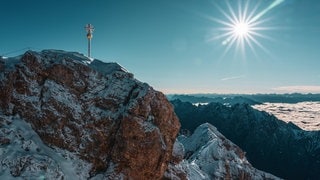 Deutschlands höchster Berg, die Zugspitze, mit Gipfelkreuz, Panoramablick bei Sonnenschein.