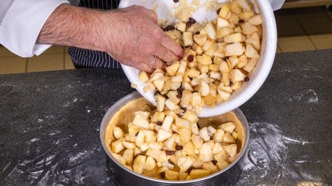 Rezept für Apfelkuchen mit Gitter: Die saftigen Apfelstückchen mit Rosinen, Mandelplättchen und weiteren Zutaten werden einfach in die Kuchenform geleert. 