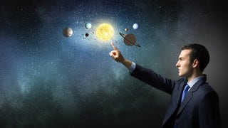 Ein Mann zeigt auf eine virtuelle Sternenkonstellation. Sternzeichen, Horoskope und Astrologie im Allgemeinen faszinieren viele Menschen.