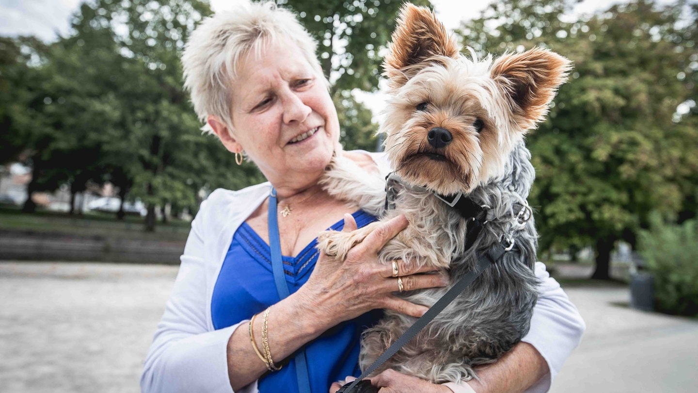 Eine Seniorin mit einem Yorkshire Terrier auf dem Arm.