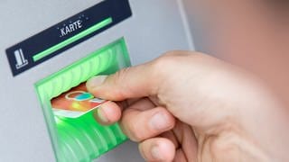 Die Gebühren für Basiskonten sind von Banken und Sparkassen erhäht worden: Bankkundin steckt ihre Girokarte in einen Geldautomaten.