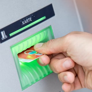 Die Gebühren für Basiskonten sind von Banken und Sparkassen erhäht worden: Bankkundin steckt ihre Girokarte in einen Geldautomaten.