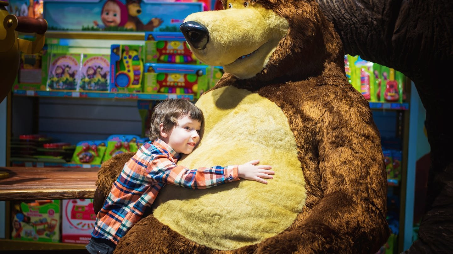 Weihnachtsgeschäft 2022: Ein Junge umarmt einen riesigen Bären in einem Spielzeugladen.