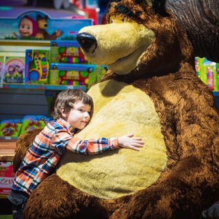 Weihnachtsgeschäft 2022: Ein Junge umarmt einen riesigen Bären in einem Spielzeugladen. 