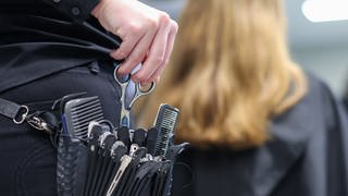 Eine Friseurmeisterin schneidet in einem Salon einer Kundin die Haare.