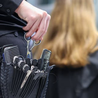 Eine Friseurmeisterin schneidet in einem Salon einer Kundin die Haare.