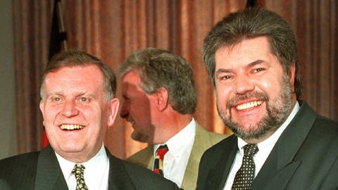 Die Ministerpräsidenten von Rheinland-Pfalz, Kurt Beck (SPD, r) und Baden-Württemberg, Erwin Teufel (CDU, l) überreichen sich am Samstag (31.5.1997) in Mainz nach der Unterzeichnung die Staatsverträge über den neuen Südwestrundfunk (SWR)