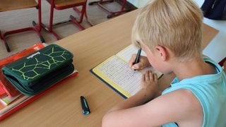 Ein Schüler sitzt im Klassenraum und arbeitet.