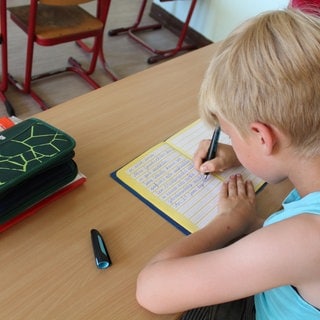 Ein Schüler sitzt im Klassenraum und arbeitet.