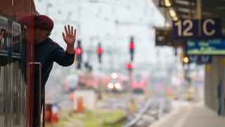 Ein Lokführer gibt kurz vor Abfahrt eines Zuges ein Handzeichen.