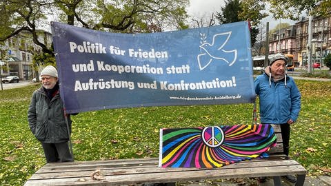 Zwei Teilnehmer der Friedensdemonstration in Heidelberg halten ein Plakat in den Händen