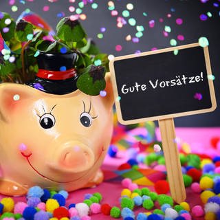 Glücksschwein mit Kleeblättern, Schornsteinfegerfigur und Schild mit Aufschrift Gute Vorsätze!