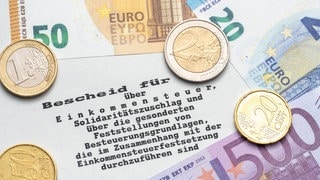 Steuerbescheid vom Finanzamt mit Euro Geldscheinen und Münzen, Einkommenssteuer und Steuererklärung Konzept