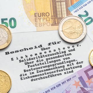 Steuerbescheid vom Finanzamt mit Euro Geldscheinen und Münzen, Einkommenssteuer und Steuererklärung Konzept