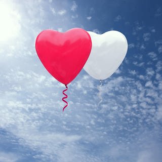Zwei Herzluftballons schweben am Himmel