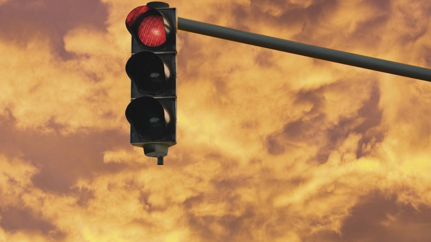 Eine Ampel zeigt Rot vor einem dramatischen Himmel