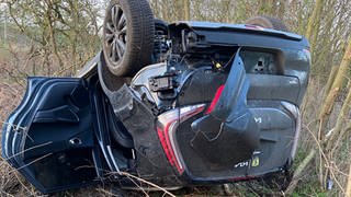 Ein Auto liegt neben der Straße auf dem Dach