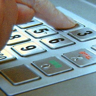 Eine Hand tippt auf der Tastatur eines Bankautomaten